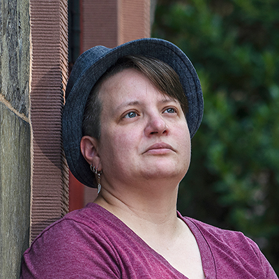 A woman with in a fedora looking up to the right.