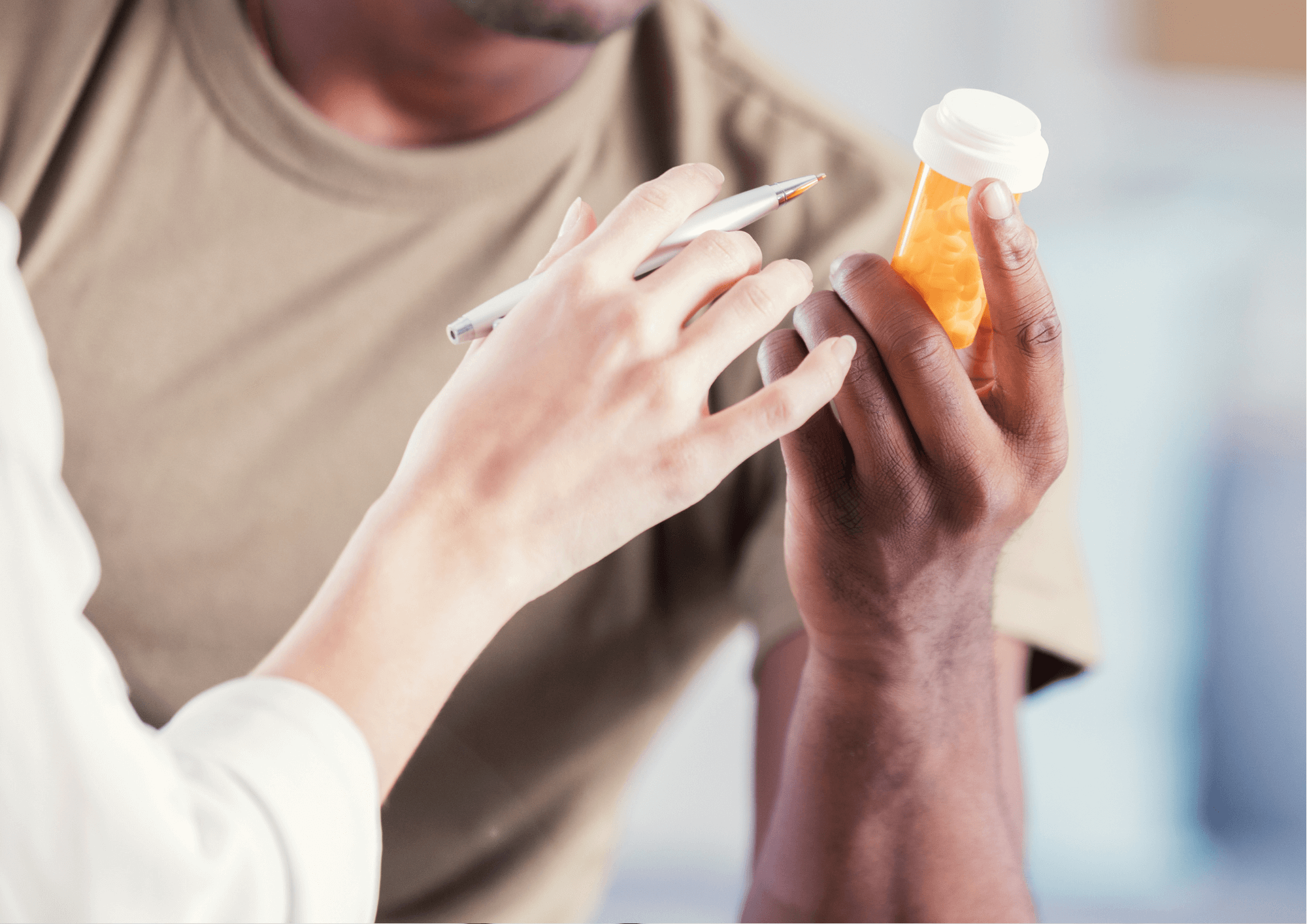 A Veteran holds a prescription bill bottle while a physician points at the label.