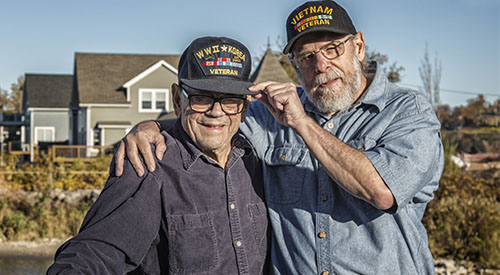 Two older men wearing caps showing Veteran service